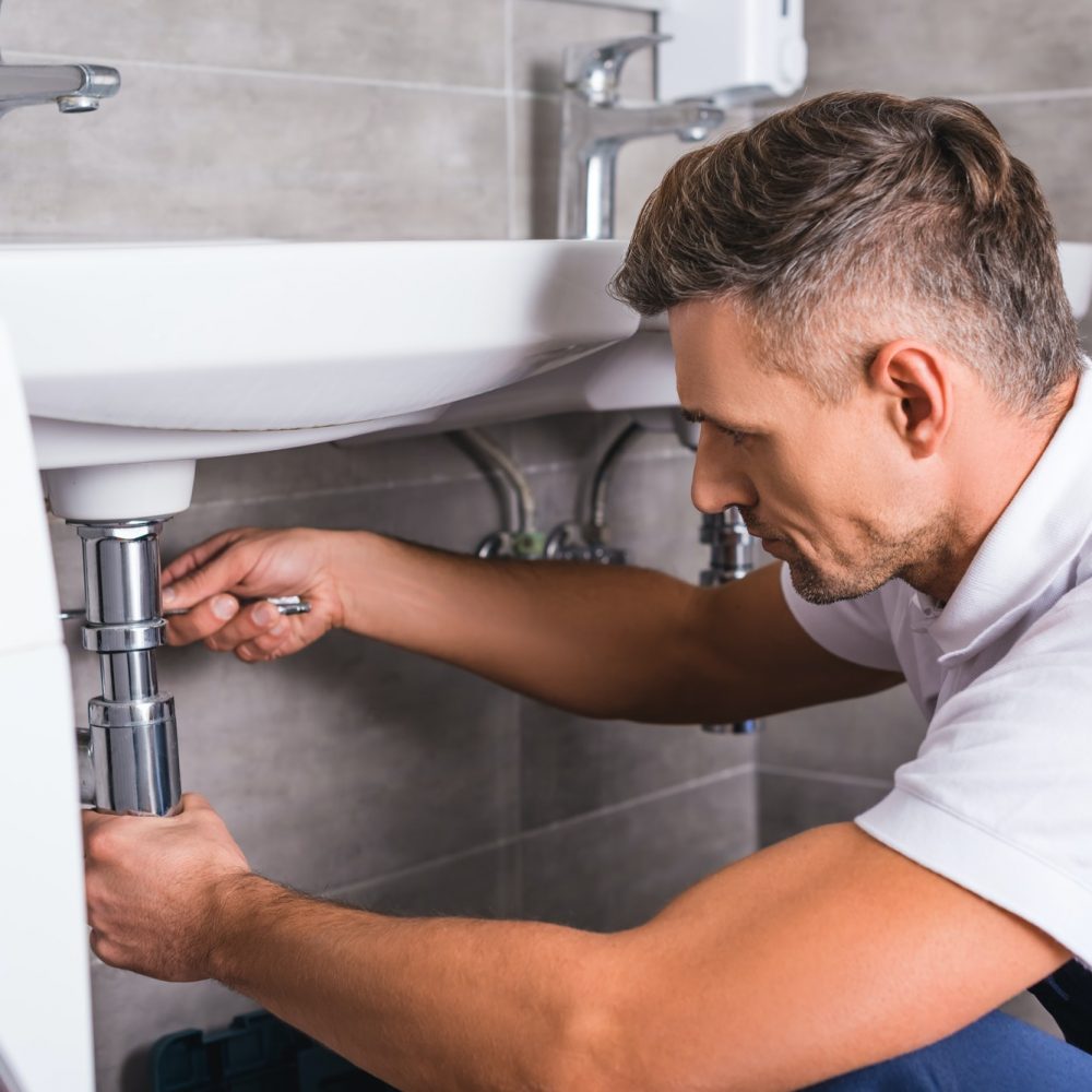 adult-plumber-fixing-sink-at-bathroom.jpg